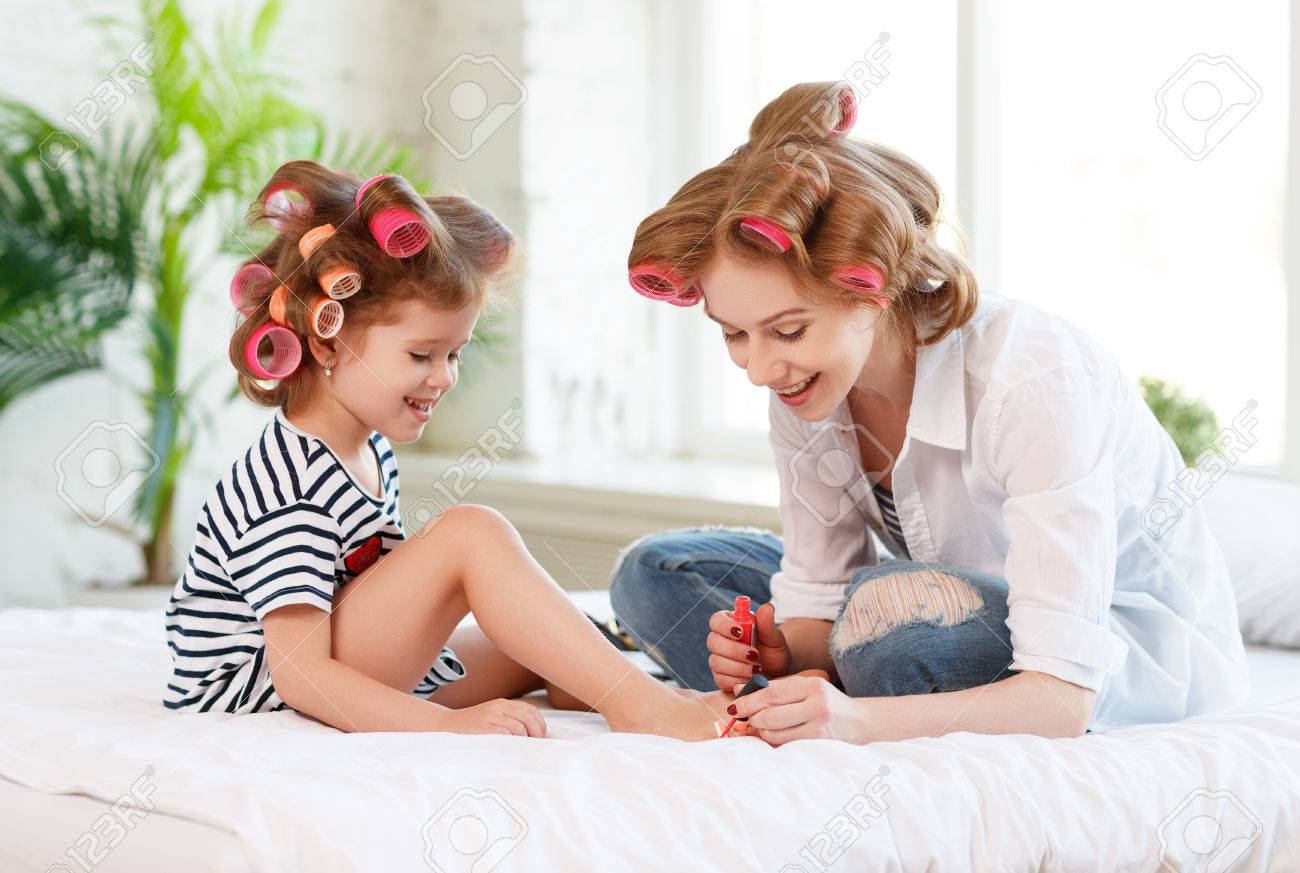 84431835 feliz madre e hija hija en rizadores de pelo pintar las unas hacer una pedicura